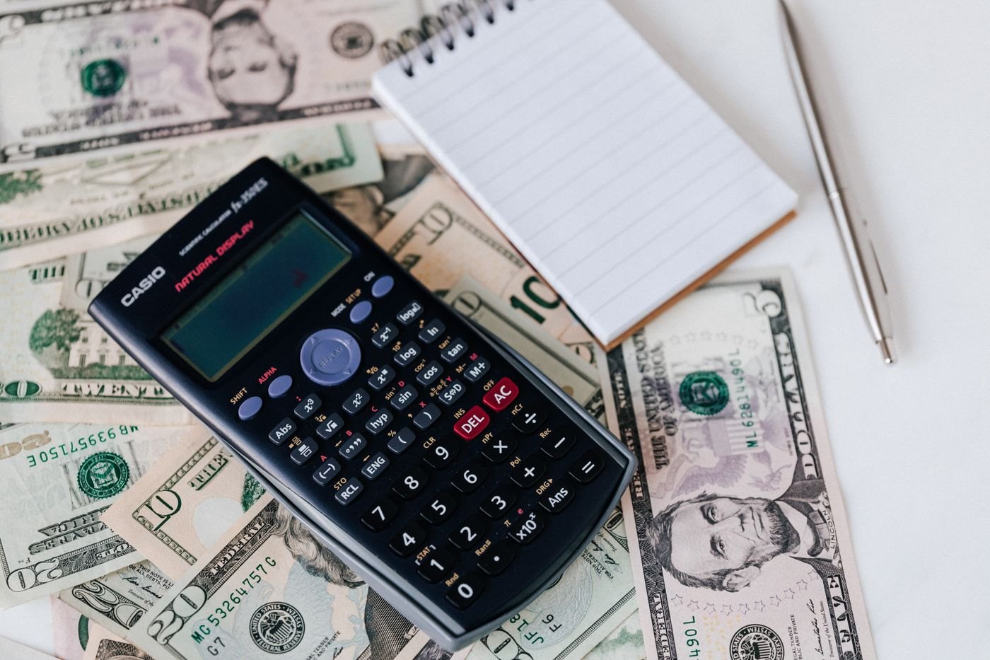 A notebook beside cash and a calculator