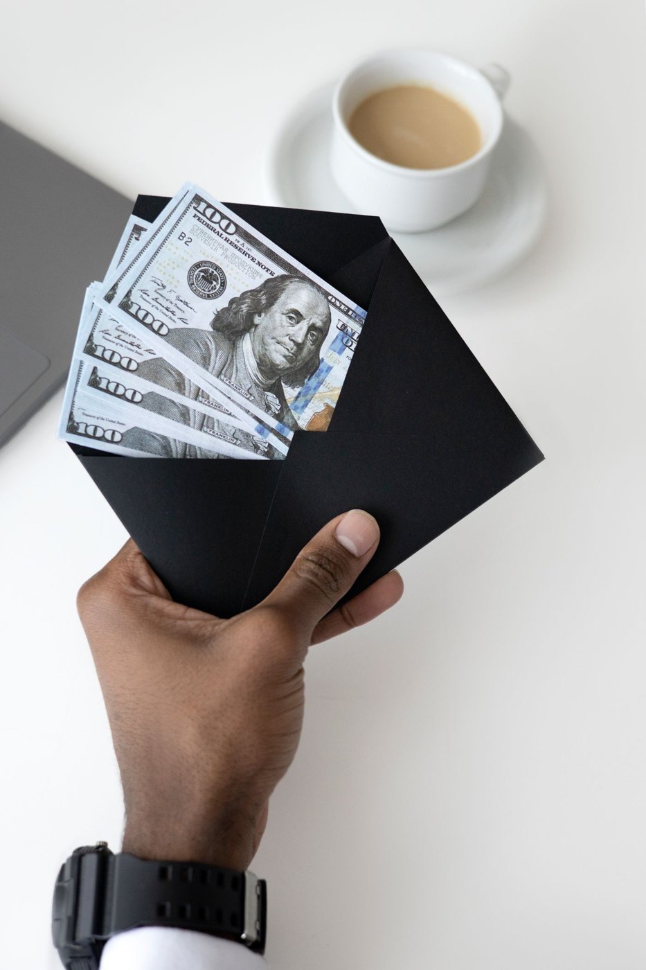 Hands holding cash inside a black envelope