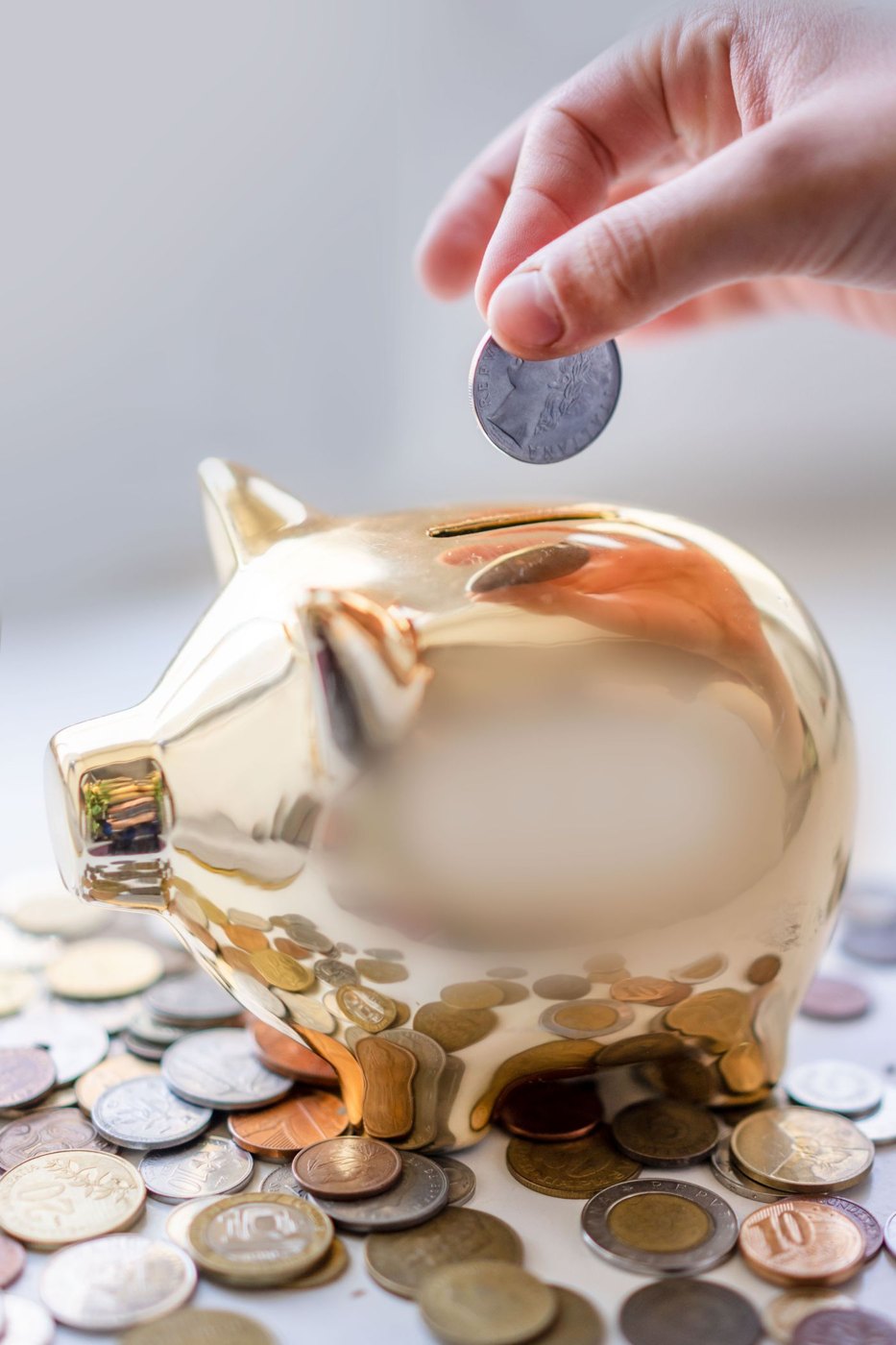 A hand adding a coin to a savings bank