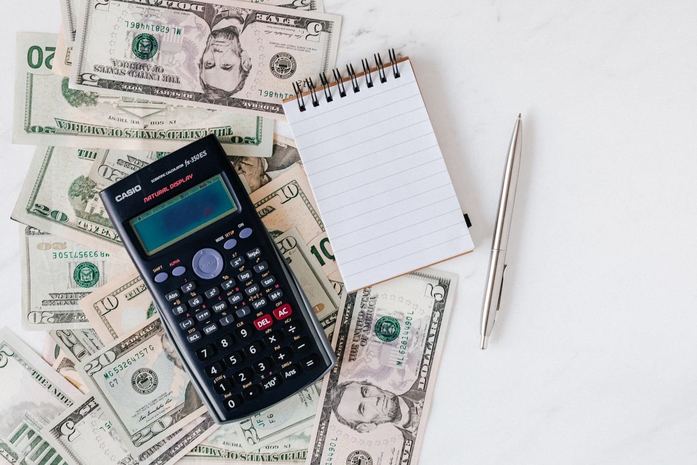 A notebook and calculator beside banknotes