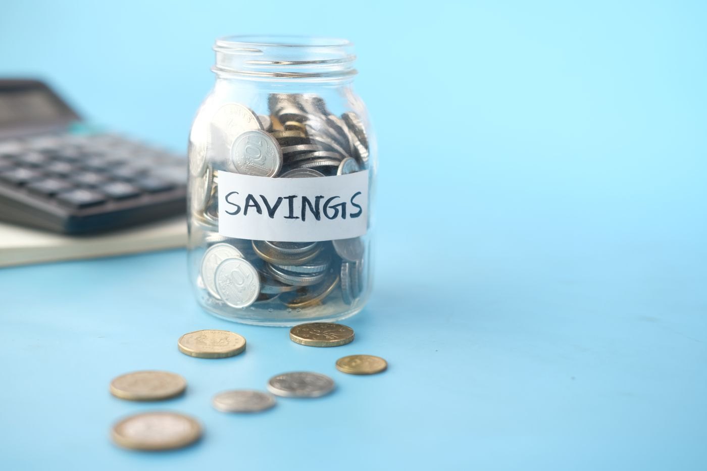 Coins collected inside a clear glass savings jar
