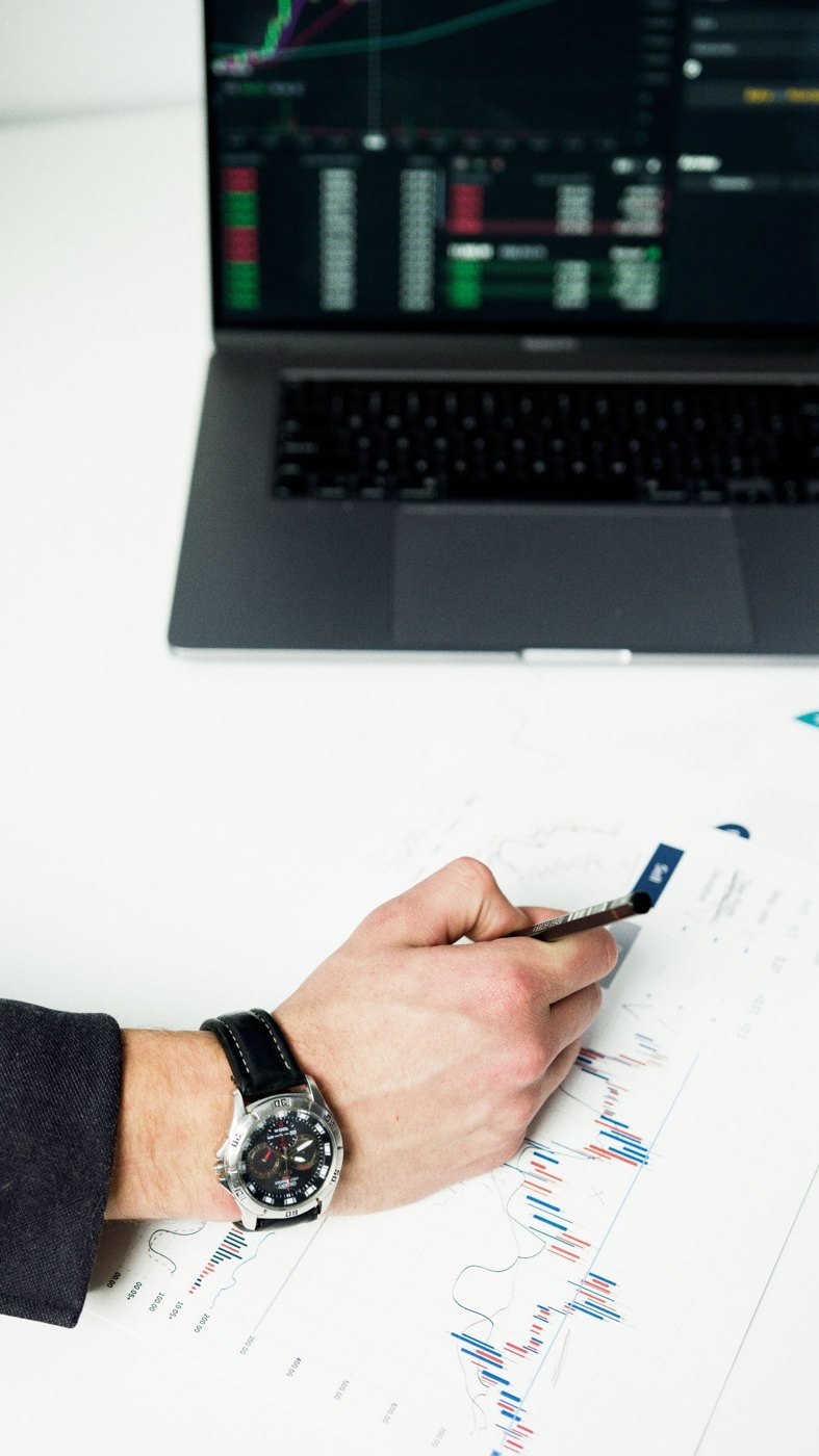 A person making notes beside investment charts