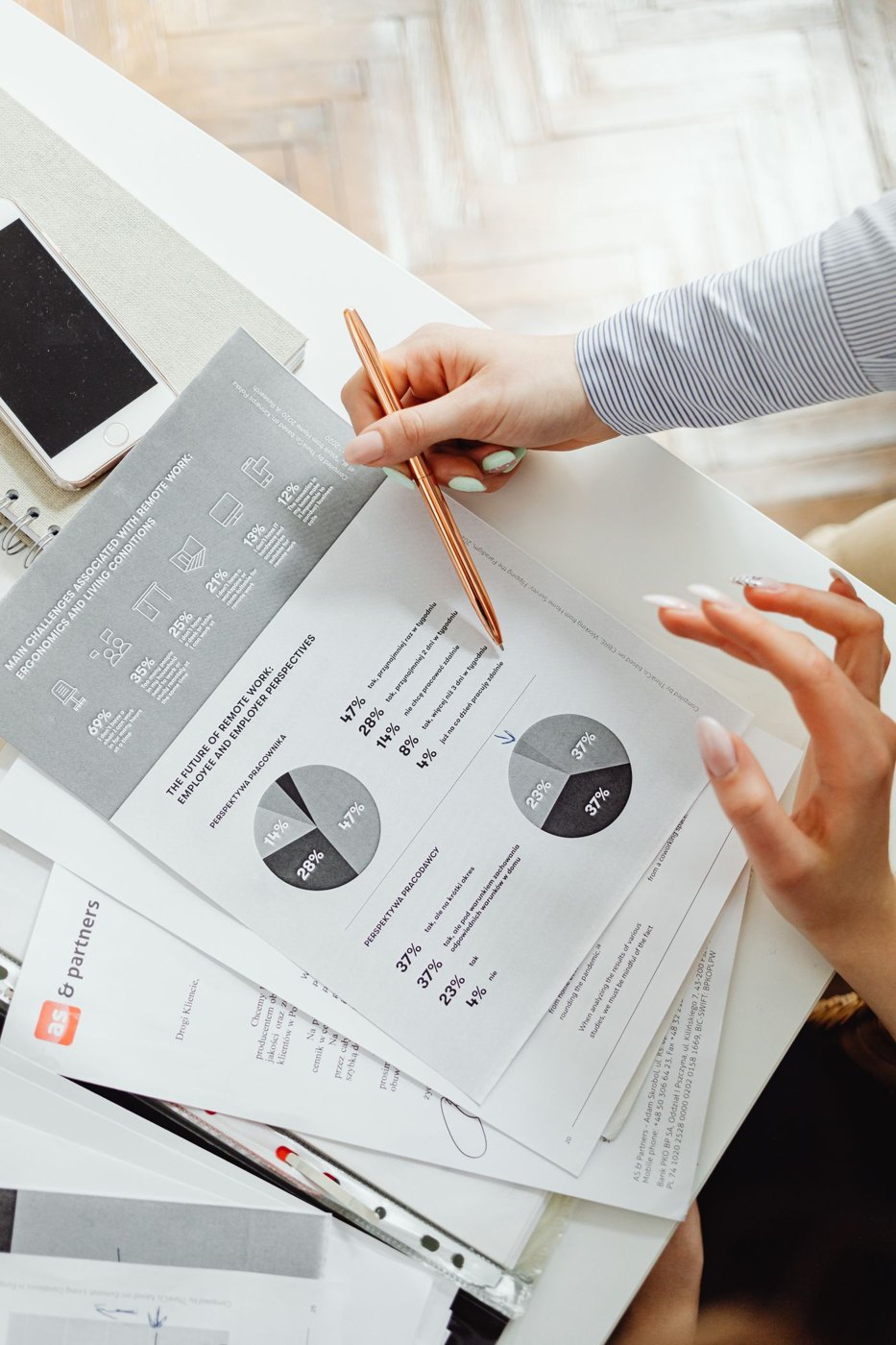 A hand reviewing pie charts in financial paperwork