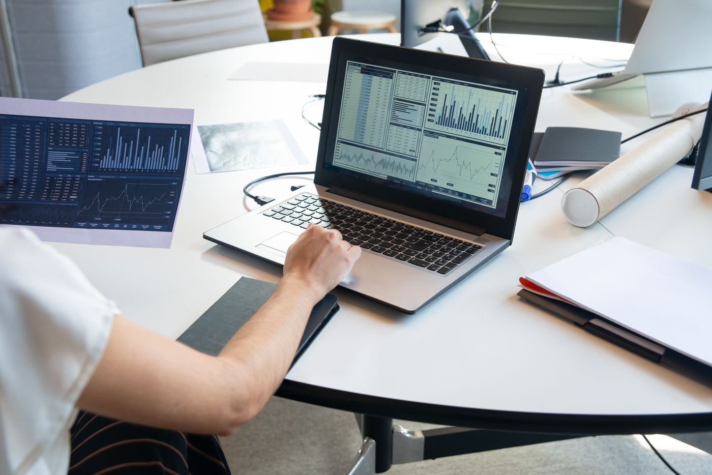 Charts on paper beside a laptop