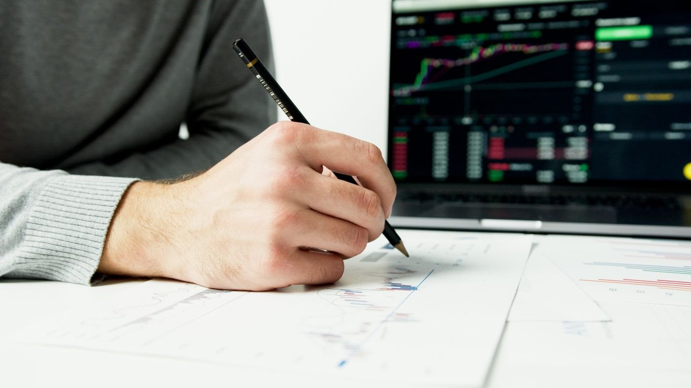 Handwritten notes being made beside financial papers