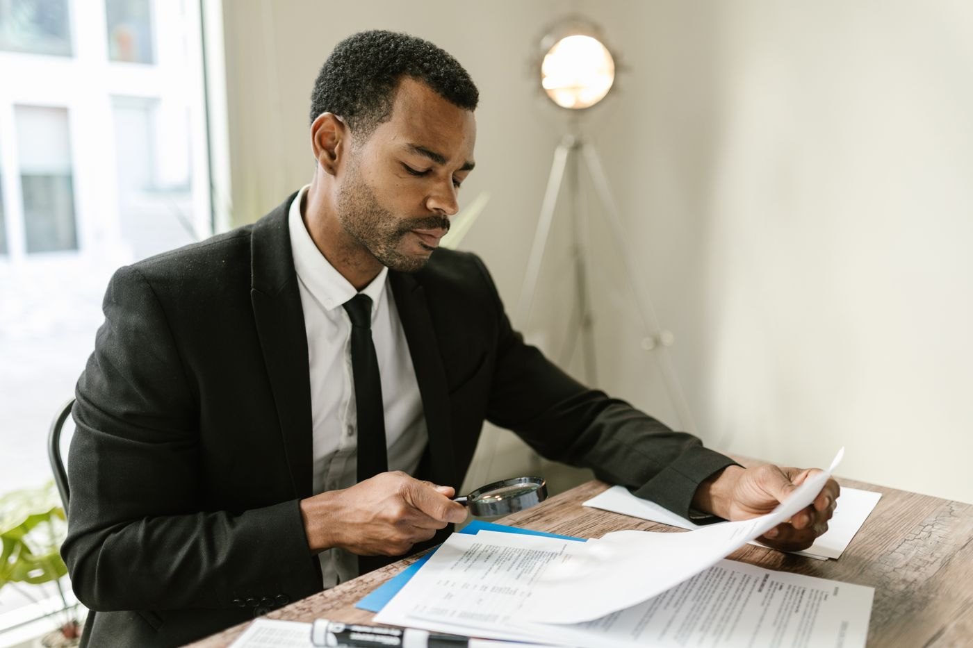 A person examining printed documents with a magnifying glass