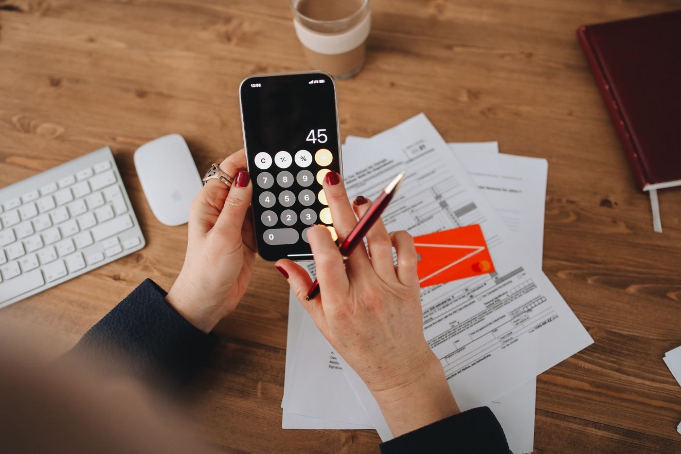 A person using a phone calculator beside household papers